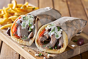 Two greek gyros with shaved lamb and french fries photo