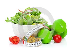 Two green dumbells, tape measure and healthy food. Fitness and h