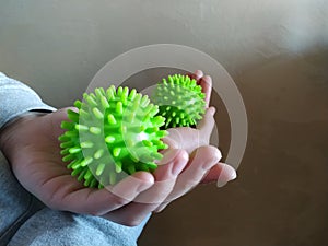 Two green massage balls looking like coronavirus moleculas in woman`s hands photo