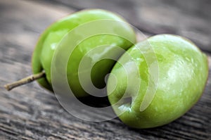 Two green olives on wooden background