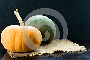 Two green and orange pumpkins on a black background. Copy space.