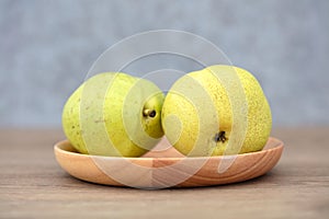 Two green pears in a wooden dish