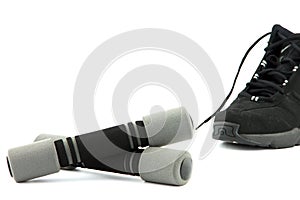 Two grey dumbbells with sneaker on background