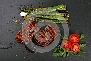 Two grilled beefsteak on black slate board