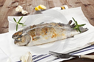 Two grilled trouts on wooden table.