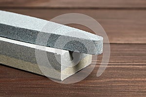 Two grindstones. Oval and rectangular double layer sharpening stone. Whetstone sharpener on wooden table