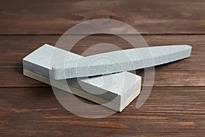 Two grindstones. Oval and rectangular double layer sharpening stone. Whetstone sharpener on wooden table background