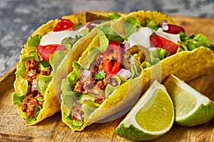 Two ground beef tacos with vegetables and lime