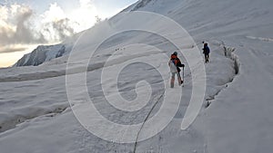 Two groups of climbers are walking in a bunch on the glacier at dawn. View from the back. Trekking from Camp 2 to Camp 1 under