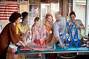 Two groups of employees making paper towers, separated in different competitive multiethnic teams