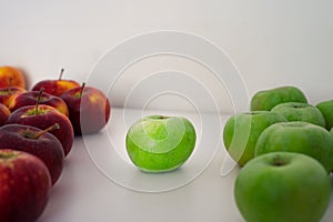 Two groups of green and red apples. One apple in the center. Organic fresh fruits and image of autumn