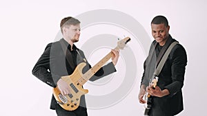 Two guitarists in black suits performing song in studio