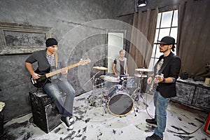 Two guitarists and drummer play in room
