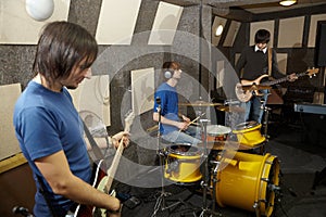 Two guitarists and drummer working in studio photo