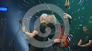 Two guitarists play together on stage at concert. Guitarists of rock band create mood. Slow motion