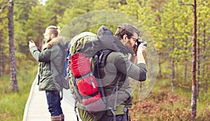 Two guys with backpacks walking in swamps and taking pictures. C