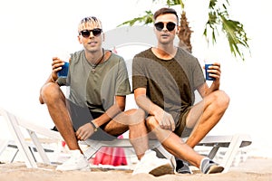 Two guys drink cocktails on a tropical beach