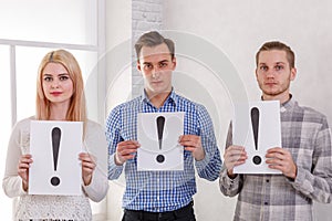 Two guys and a girl stand next to keep the sheets with exclamation marks