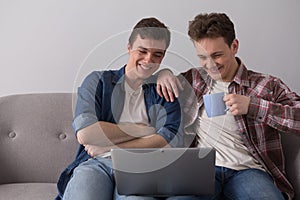 Two guys with laptop on sofa.