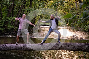 Two guys play funnily fighting in martial arts style on a log bridge