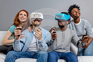 Two guys playing video games using VR glasses and girlfriends support them.