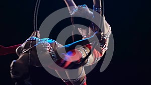 Two gymnasts spinning in the air on a hoop. Black smooke background. Slow motion. Close up