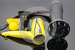 Two hair dryers with accessory on the grey mirror background