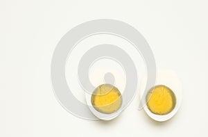 Two half boiled peeled egg in a white cup on a white background