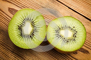 Two half kiwis on a wooden table