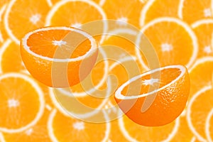 Two half oranges in front of a blurred orange slices