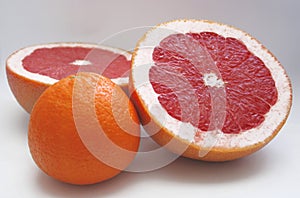 Two halfs of red grape fruit and an orange