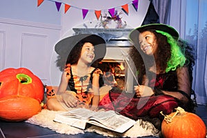 Two Halloween laughing girls with magic book