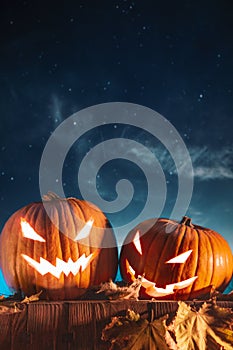 Two halloween pumpkins on fence with starry sky