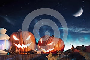 Two halloween pumpkins on fence with starry sky