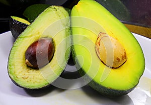 Two halves of an avocado with seeds and placed on a plate