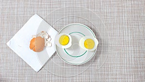 Two halves of a boiled egg on a plate, near which there is an eggshell