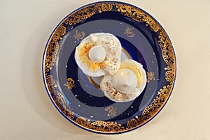 Two halves of boiled egg with sauce and pepper