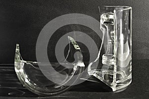 Two halves of a broken cup stand on a black background. Broken