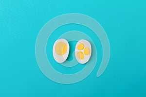 Two halves of a chicken egg with one yolk and three yolks on a blue background