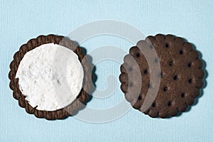 Two halves of chocolate-cream cookies on a blue background