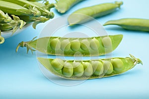 Two halves of a cracked pod of fresh peas on a blue background