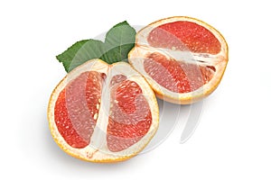 Two halves of grapefruit with green leaves isolated on white background