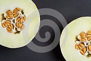 Two halves of an Ivory gaya melon on a dark background, close up