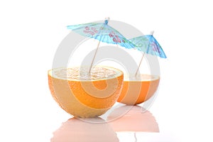 Two halves of an orange with cocktail umbrellas