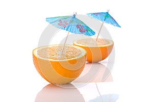 Two halves of an orange with cocktail umbrellas