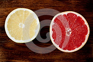 Two halves of red and white grapefruit, bright circles on a dark wooden background. citrus fruits