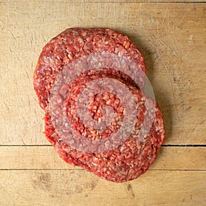 Two hamburger patties top view on an old wood cutting board