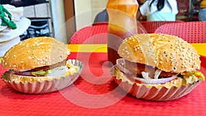 Two hamburgers on a red tablecloth in a fast food restaurant