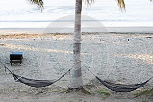 Two hammocks hanging on beach.