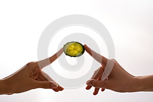 Two hand holding the slice of cucumber on white background